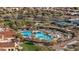Aerial view of community pool with palm trees, umbrellas and tennis courts surrounded by lush landscaping at 26880 W Sierra Pinta Dr, Buckeye, AZ 85396
