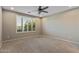 A cozy bedroom with carpet, a ceiling fan, a window with wood shutters, and neutral wall paint at 26880 W Sierra Pinta Dr, Buckeye, AZ 85396