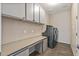 Functional laundry room with washer, dryer, ample counter space, and storage cabinets for organization at 26880 W Sierra Pinta Dr, Buckeye, AZ 85396