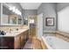 Well-lit bathroom featuring double sinks, a soaking tub, and a separate glass-enclosed shower at 4121 E Ashurst Dr, Phoenix, AZ 85048