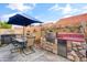 Outdoor kitchen area featuring a stone surround BBQ, sink, table, and hot tub under a blue patio umbrella at 4121 E Ashurst Dr, Phoenix, AZ 85048