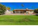 Expansive backyard featuring lush green grass, mature trees, and a covered patio at 5123 E Beck Ln, Scottsdale, AZ 85254