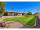 Spacious backyard featuring a well-manicured lawn, mature trees, and a covered patio at 5123 E Beck Ln, Scottsdale, AZ 85254