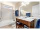 Bright bathroom with a vanity, a large mirror, a tub with a shower, and natural light at 5123 E Beck Ln, Scottsdale, AZ 85254