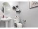 Cozy powder room with pedestal sink, toilet, neutral paint, and decorative shelving at 5145 W Odeum Ln, Phoenix, AZ 85043