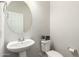 This half bathroom contains a pedestal sink, toilet and round mirror at 5721 W Getty Dr, Phoenix, AZ 85043