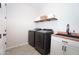 Practical laundry room with front load washer/dryer, sink, and floating shelves for efficient organization at 632 W Springfield Pl, Chandler, AZ 85286