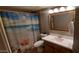 Cozy bathroom with beach-themed shower curtain and a framed mirror above a single sink vanity at 6943 W Devonshire Ave # 1355, Phoenix, AZ 85033