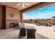 Inviting covered outdoor patio with a stone fireplace, comfortable seating, and view of the pool and waterfall at 10902 N 138Th Pl, Scottsdale, AZ 85259