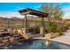 Lush pool area featuring a rock waterfall, desert landscaping, and a charming pergola with seating at 10902 N 138Th Pl, Scottsdale, AZ 85259