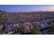 Expansive aerial view of desert homes showcasing tile roofs and desert landscaping against a mountain backdrop and city lights at 10999 E Acoma Dr, Scottsdale, AZ 85255