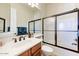 Bright bathroom features a wood vanity, modern fixtures, and shower with frosted glass doors at 10999 E Acoma Dr, Scottsdale, AZ 85255