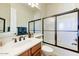 Cozy bathroom featuring a vanity with dark fixtures and a shower with a sliding glass door at 10999 E Acoma Dr, Scottsdale, AZ 85255