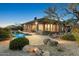 Exterior view of the property showcases the backyard with a desert landscape and custom pool at 10999 E Acoma Dr, Scottsdale, AZ 85255