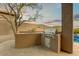 Outdoor kitchen and BBQ area complemented by desert landscaping and picturesque mountain views at 10999 E Acoma Dr, Scottsdale, AZ 85255