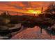 Stunning pool reflects vibrant sunset, complemented by rock features and manicured landscaping at 10999 E Acoma Dr, Scottsdale, AZ 85255