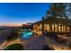 Backyard pool and patio with outdoor seating, water feature, desert landscaping, and views of mountain range at twilight at 10999 E Acoma Dr, Scottsdale, AZ 85255