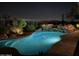 Inviting pool with rock waterfall feature is beautifully lit at night for serene relaxation at 10999 E Acoma Dr, Scottsdale, AZ 85255
