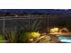 Pool with stone accents and colorful desert landscaping, surrounded by a rod iron fence with city views in the background at 10999 E Acoma Dr, Scottsdale, AZ 85255