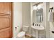 Well-lit powder room with a pedestal sink, mirror, and toilet at 10999 E Acoma Dr, Scottsdale, AZ 85255