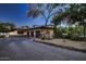 Home featuring a three-car garage with stone accents, tile roof, and a paved driveway surrounded by desert landscaping at 11021 N 74Th St, Scottsdale, AZ 85260