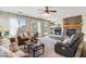 Cozy living room with a stone fireplace, large windows, and comfortable brown seating arrangements at 11933 N 140Th Ln, Surprise, AZ 85379