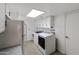 Well-lit laundry area featuring white appliances and cabinets, complemented by vintage black and white tile flooring at 1655 W Meseto Cir, Mesa, AZ 85202