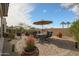 A beautiful backyard featuring a dining area under an umbrella, surrounded by lush plants and a charming desert landscape at 16712 S 175Th Ln, Goodyear, AZ 85338