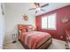 Bedroom with a ceiling fan, red accent wall, and plantation shutters at 16712 S 175Th Ln, Goodyear, AZ 85338