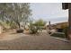 Spacious desert landscaped backyard featuring gravel, mature trees, and a charming patio set at 17662 W Cedarwood Ln, Goodyear, AZ 85338