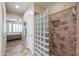 Bathroom featuring a glass block partition shower with tile surround, and a view to the bedroom at 17662 W Cedarwood Ln, Goodyear, AZ 85338
