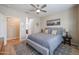 Bedroom featuring a grey fabric bed, a ceiling fan, and a view into the ensuite bathroom at 17662 W Cedarwood Ln, Goodyear, AZ 85338