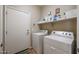 Bright laundry room features a washer, dryer, storage shelf, and convenient access door at 17662 W Cedarwood Ln, Goodyear, AZ 85338