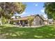 Expansive backyard with lush green grass, mature trees, and a patio area for outdoor dining at 20215 N Medallion Ct, Sun City West, AZ 85375