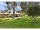 Picturesque backyard featuring mature trees, lush green grass, and a view of the home's exterior at 20215 N Medallion Ct, Sun City West, AZ 85375
