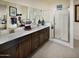 Bright bathroom with double sinks, sleek countertops, a glass-enclosed shower, and ample vanity storage at 41905 W Hospitality Ln, Maricopa, AZ 85138