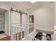Upstairs hallway with a barn door leading to a closet, complemented by white railings and views of the downstairs living area at 6229 N 30Th Way, Phoenix, AZ 85016