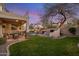 Inviting backyard with pool, patio, outdoor seating, lush lawn, built-in grill, and ambient string lights for evening relaxation at 7501 E Phantom Way, Scottsdale, AZ 85255