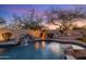 Beautiful backyard featuring a pool with a waterfall, outdoor kitchen, and ambient lighting for evening enjoyment at 7501 E Phantom Way, Scottsdale, AZ 85255
