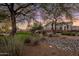 Beautifully landscaped home exterior with mature trees, green lawn, and rock features at 7501 E Phantom Way, Scottsdale, AZ 85255