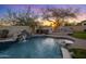 Backyard oasis with a pool, waterfall, spa, and outdoor fireplace with sunset at 7501 E Phantom Way, Scottsdale, AZ 85255