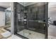 Glass enclosed shower with gray textured wall tiles, penny tile floor and storage niche at 7501 E Phantom Way, Scottsdale, AZ 85255