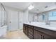 Bathroom with dual sinks, white countertops, sleek cabinetry, glass-enclosed shower, and natural light at 12219 W Caraveo Pl, Peoria, AZ 85383