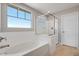 Bright bathroom showcasing a soaking tub, glass-enclosed shower, and natural light from a large window at 12219 W Caraveo Pl, Peoria, AZ 85383