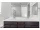 A bathroom featuring a double sink vanity with framed mirrors and dark wood cabinets at 17057 W Seldon Ln, Waddell, AZ 85355