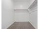 A walk-in closet featuring carpet flooring, a wooden hanging bar, and bright white walls at 17057 W Seldon Ln, Waddell, AZ 85355