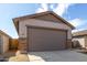 Two car garage with brown door, with a concrete driveway and desert landscaping at 17057 W Seldon Ln, Waddell, AZ 85355