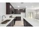 An open-concept kitchen featuring stainless steel appliances, dark wood cabinets, and a large island with white countertops at 17057 W Seldon Ln, Waddell, AZ 85355