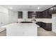 A modern kitchen features stainless steel appliances, dark wood cabinets, and a large island with white countertops at 17057 W Seldon Ln, Waddell, AZ 85355