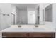 Bathroom featuring dual sinks, a large mirror, modern fixtures, and brown cabinetry at 17081 W Seldon Ln, Waddell, AZ 85355